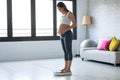 Pretty young pregnant woman standing on scales at home Royalty Free Stock Photo