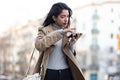 Pretty young woman consulting the map on her mobile phone while walking in the street Royalty Free Stock Photo