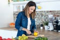 Pretty young woman cutting lemons for preparing detox beverage in the kitchen at home Royalty Free Stock Photo