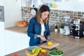 Pretty young woman cutting lemons for preparing detox beverage in the kitchen at home Royalty Free Stock Photo