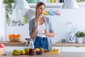 Pretty young woman eating yogurt while standing in the kitchen at home Royalty Free Stock Photo