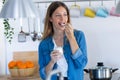 Pretty young woman eating yogurt while standing in the kitchen at home Royalty Free Stock Photo