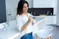 Pretty young woman eating yogurt while standing in the kitchen at home Royalty Free Stock Photo