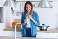 Pretty young woman eating yogurt while standing in the kitchen at home Royalty Free Stock Photo