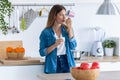 Pretty young woman eating yogurt while standing in the kitchen at home Royalty Free Stock Photo