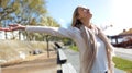 Pretty young woman enjoying the spring with arms raised to the sky on the street Royalty Free Stock Photo