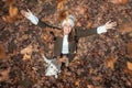 Pretty young woman with her dog looking to the sky with arms raised as leaves fall from the trees in the park in autumn. Royalty Free Stock Photo