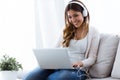 Pretty young woman listening to music while using her laptop at home. Royalty Free Stock Photo