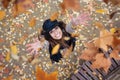 Pretty young woman looking to the sky with arms raised as leaves fall from the trees in the park in autumn Royalty Free Stock Photo