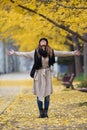 Pretty young woman looking to sky with arms raised and having fun in the park in autumn Royalty Free Stock Photo