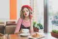 Shot of pretty young woman sitting and drinking coffee in a caffee while holding the smartphone and looking sideways Royalty Free Stock Photo