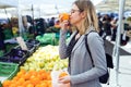Pretty young woman smelling orange in the street market. Royalty Free Stock Photo