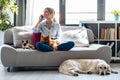 Pretty young woman talking with mobile phone while sitting in couch with her dogs and cat at home Royalty Free Stock Photo
