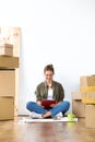 Pretty young woman using her digital tablet while sitting on the floor of her new house. Royalty Free Stock Photo