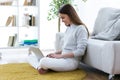 Pretty young woman using her laptop while sitting on the floor at home. Royalty Free Stock Photo