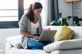 Pretty young woman using her laptop while sitting on sofa at home Royalty Free Stock Photo