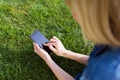 Pretty young woman using her mobile phone while lying on grass in the park. Royalty Free Stock Photo