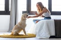 Pretty young woman using her mobile phone while staying with her dog at home Royalty Free Stock Photo