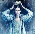 The ice queen cometh. Shot of queen holding a crown over her head with snow falling around her. Royalty Free Stock Photo