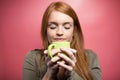 Quiet beautiful woman smelling coffee over pink background