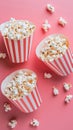 shot of red striped popcorn boxes on pink surface, scattered kernels the playful movie vibe.