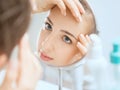 Shot of a reflection of a young woman examining her face