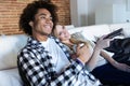 Relaxed young couple changing channels with the remote control while watching TV on the sofa at home Royalty Free Stock Photo