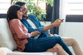 Relaxed young couple changing channels with the remote control while watching TV on the sofa at home Royalty Free Stock Photo