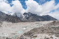 Shot of a rocky and icy terrain with high snowy mountains and a blue cloudy sky over them Royalty Free Stock Photo