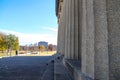 A shot of rows of tall stone pillars at The Parthenon with clear blue sky and autumn colored trees and lush green trees