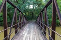 A shot of a rust colored iron bridge covered in fallen leaves over the brown waters of the Chattahoochee silky brown river Royalty Free Stock Photo