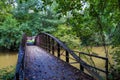 A shot of a rust colored iron bridge covered in fallen leaves over the brown waters of the Chattahoochee silky brown river Royalty Free Stock Photo