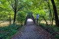 A shot of a rust colored iron bridge covered in fallen leaves over the brown waters of the Chattahoochee silky brown river