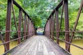 A shot of a rust colored iron bridge covered in fallen leaves over the brown waters of the Chattahoochee silky brown river Royalty Free Stock Photo