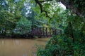 A shot of a rust colored iron bridge covered in fallen leaves over the brown waters of the Chattahoochee silky brown river Royalty Free Stock Photo