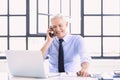 Shot of senior businessman using laptop and making a phone call while working at the office Royalty Free Stock Photo