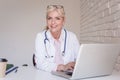 Smiling female doctor working on laptop at the doctor`s office Royalty Free Stock Photo