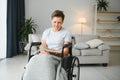 Shot of a senior woman sitting in a wheelchair and reading book at home Royalty Free Stock Photo