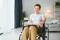 Shot of a senior woman sitting in a wheelchair and reading book at home Royalty Free Stock Photo