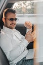 Stylish businessperson with cellphone looking at camera inside car Royalty Free Stock Photo