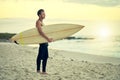 Surfing isnt a hobby, its a lifestyle. Shot of a shirtless young surfer watching the waves while holding his surfboard Royalty Free Stock Photo
