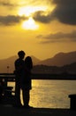 Shot of the silhouette of a hugging couple by a lake, the mountains on the horizon, at the sunset Royalty Free Stock Photo