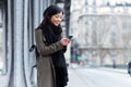 Smiling asian young woman using her mobile phone in the street. Royalty Free Stock Photo