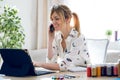 Smiling beautiful young designer woman working with her digital tablet while talking with her mobile phone at the office Royalty Free Stock Photo