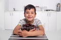 Shot of a smiling boy sitting in the kitchen and hugging a large bowl of  cherries Royalty Free Stock Photo