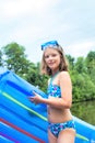 Shot of smiling girl in swimwear standing with pool raft at lakeshore