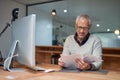 He always reads the fine print. Shot of a smiling mature businessman reading paperwork while sitting at his desk in an Royalty Free Stock Photo