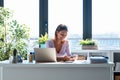 Smiling young business woman using her mobile phone while working with computer in the office at home Royalty Free Stock Photo