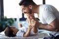 Smiling young father has fun with little baby while changing his nappy at home Royalty Free Stock Photo