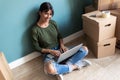 Smiling young woman working with laptop while looking at camera sitting on the floor at home Royalty Free Stock Photo